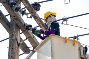 electricistas que trabajan en el teleférico para reparar la línea eléctrica bajo un fondo de cielo azul claro. foto