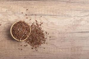 semillas de lino en un cuenco de madera sobre un fondo de madera, vista superior foto