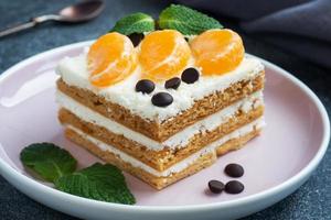 Sponge cake layers with buttercream, decorated with slices of tangerine chocolate and mint. Delicious sweet dessert for tea. photo