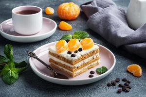 capas de bizcocho con buttercream, decoradas con láminas de chocolate mandarina y menta. delicioso postre dulce para el té. foto