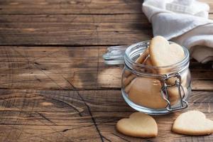 Homemade cookies in the shape of hearts in a glass jar, wooden background. The concept of Valentine's Day. copy space. photo