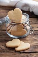 Homemade cookies in the shape of hearts in a glass jar, wooden background. The concept of Valentine's Day. photo