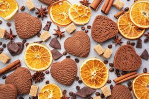 Chocolate heart cookies, oranges cinnamon and spicy spices on a gray table, top view, close up. photo