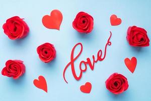 la palabra amor y corazones rojos rosas sobre un fondo azul, vista superior. tarjeta de vacaciones para el día de san valentín. endecha plana foto