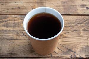 Black coffee in a paper cup on a wooden background. flat lay copy space, top view. photo