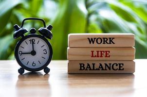 Alarm clock pointing at 9am with work life balance text on wooden blocks. Work life balance concept photo