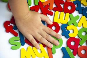 Hand pressing wooden color letters on white background. photo