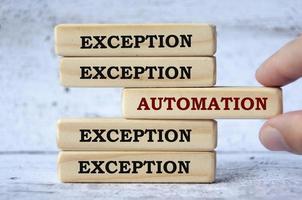 Exception and automation text on wooden blocks with hand placing a wooden block in the middle. photo
