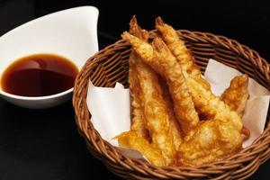 fried king prawns in batter, in a wicker basket on a black background photo