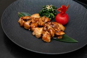 Kung Pao Chicken or Gong Bao Ji Ding at dark slate background. Sichuan Kung Pao is chinese cuisine dish with chicken meat, chilli peppers, peanuts, sauces and onion. photo