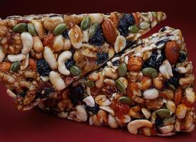 Two pieces of gozinak from various nuts with dried fruits on a red background. photo