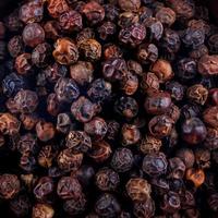 Black pepper grains as background close up photo