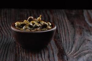 Pickled capers in a clay cup on a wooden table. photo