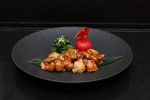 Kung Pao Chicken or Gong Bao Ji Ding at dark slate background. Sichuan Kung Pao is chinese cuisine dish with chicken meat, chilli peppers, peanuts, sauces and onion. photo