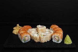 sushi en un plato de piedra con fondo negro foto