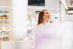 mujer adulta muy sonriente con cabello oscuro en la tienda de cosméticos y perfumes, compras navideñas foto