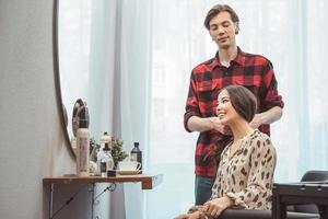 Stylist barber styling long hair for beautiful asian young woman in the beauty salon, working moment photo