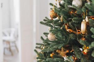 árbol de navidad decorado con juguetes dorados y blancos con las luces de fondo texturizado foto