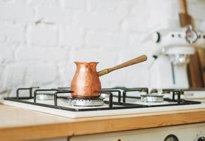 cafetera de cobre en la estufa en la cocina luminosa, rutina matutina foto