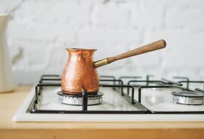 cafetera de cobre en la estufa en la cocina luminosa, rutina matutina foto