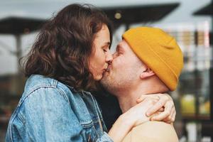 feliz pareja familiar joven y elegante enamorada de los hipsters divirtiéndose contra la pared de cristal foto