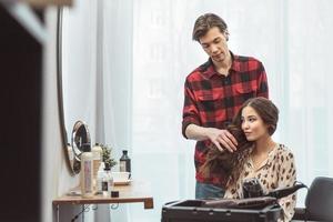 peluquero estilista peinando cabello largo para una hermosa joven asiática en el salón de belleza, momento de trabajo foto