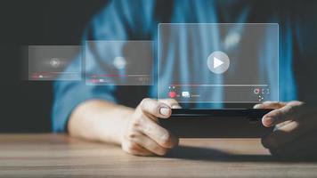 Man using a smartphone or mobile phone for streaming online on virtual screen, searching video on internet, live football, show or tutorial, watching the movies, content online. photo