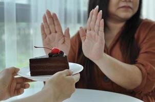 Fat woman pushes the plate onto a chocolate cake. Intention to lose weight for good health and good shape