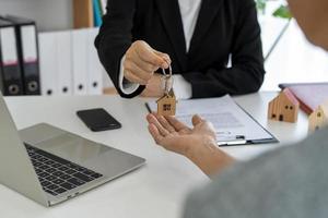 los agentes inmobiliarios entregan la llave al propietario después de un acuerdo de compra-venta.