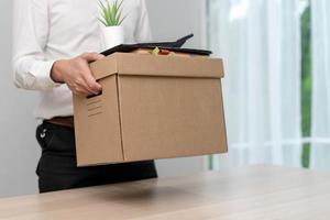 A businessman holds a box for personal items after sending a resignation letter to an executive or boss. Include information about resignation and vacancies and job changes. photo
