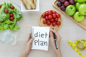 una mesa de comedor con frutas, verduras y un plan de dieta. foto
