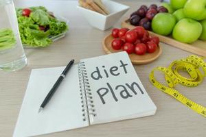 A dining table with fruits, vegetables and a diet plan. photo