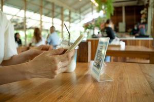 la gente usa el teléfono inteligente para escanear el código qr en el café. el restaurante construyó un sistema de pago digital sin efectivo. pago con código qr, billetera electrónica, tecnología de efectivo, pago en línea foto