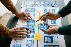 Close up view of UI developer team brainstorming on their project with laptop, smartphone and digital tablet. Creative digital development agency. photo