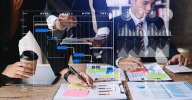 Businessman hand Project manager working and update tasks and Gantt chart scheduling virtual diagram.with smart phone, tablet and laptop in office. photo