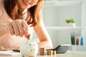 Women are putting coins in a piggy bank for a business that grows for profit and saving money for the future. planning for retirement concept photo