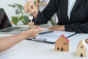 los agentes inmobiliarios entregan la llave al propietario después de un acuerdo de compra-venta.