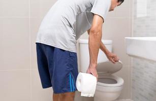 Man standing in bathroom holding tissues with severe stomach pain. stomach cramps, Abdominal pain, Diarrhea, Colon or belly cancer photo