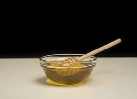 dripping honey on wooden dipper white background with room for copy space photo