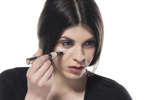young woman apply concealer under the eye photo