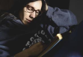 woman relaxing on sofa and reading book. evening moody ambience. she is enjoying time during weekend photo