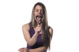 Laughing woman holds a magnifying glass in front of her mouth photo