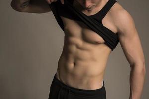 A fit young man pinching body fat on his body photo
