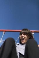 An infantile and happy woman sitting on a kid slide on a playground photo