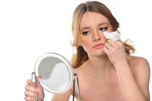 Beautiful brunette woman removing makeup from her face photo