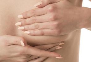 mano de mujer revisando bultos en su seno para detectar signos de cáncer de seno foto