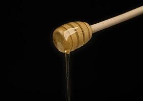 dripping honey on wooden dipper white background with room for copy space photo