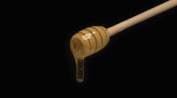 dripping honey on wooden dipper white background with room for copy space photo