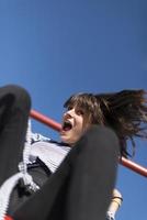 An infantile and happy woman sitting on a kid slide on a playground photo