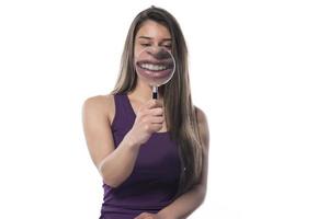 Laughing woman holds a magnifying glass in front of her mouth photo